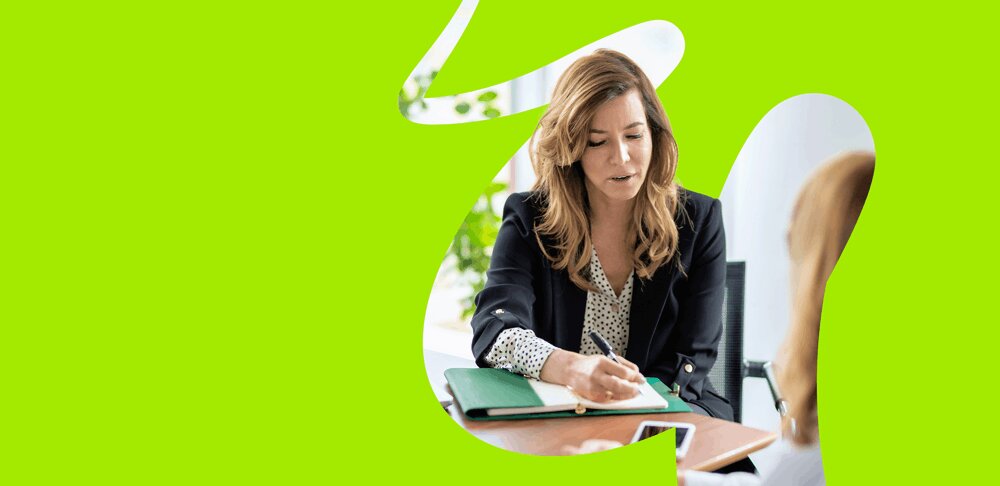 Woman writing notes on Embridge Consulting's ERP consultancy and strategic advisory services in a meeting.