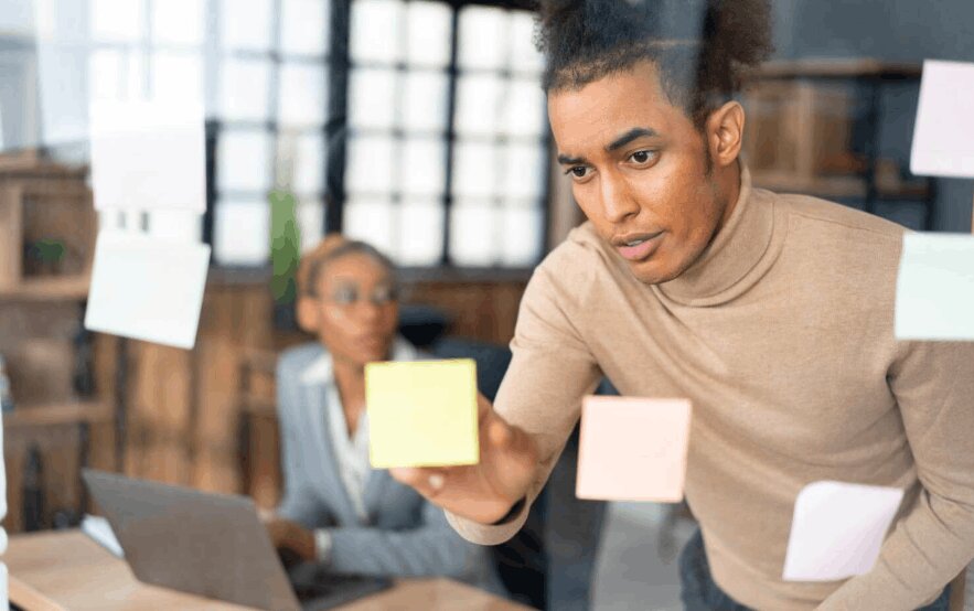 Man using sticky notes to plan business transformation solutions and managed ERP services.